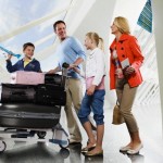 Family with two children (10-12, 13-15) pushing trolley through airport
